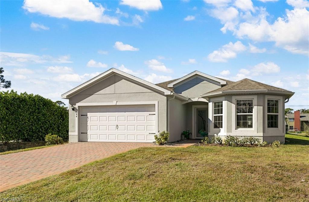 Ranch-style house with a garage and a front lawn