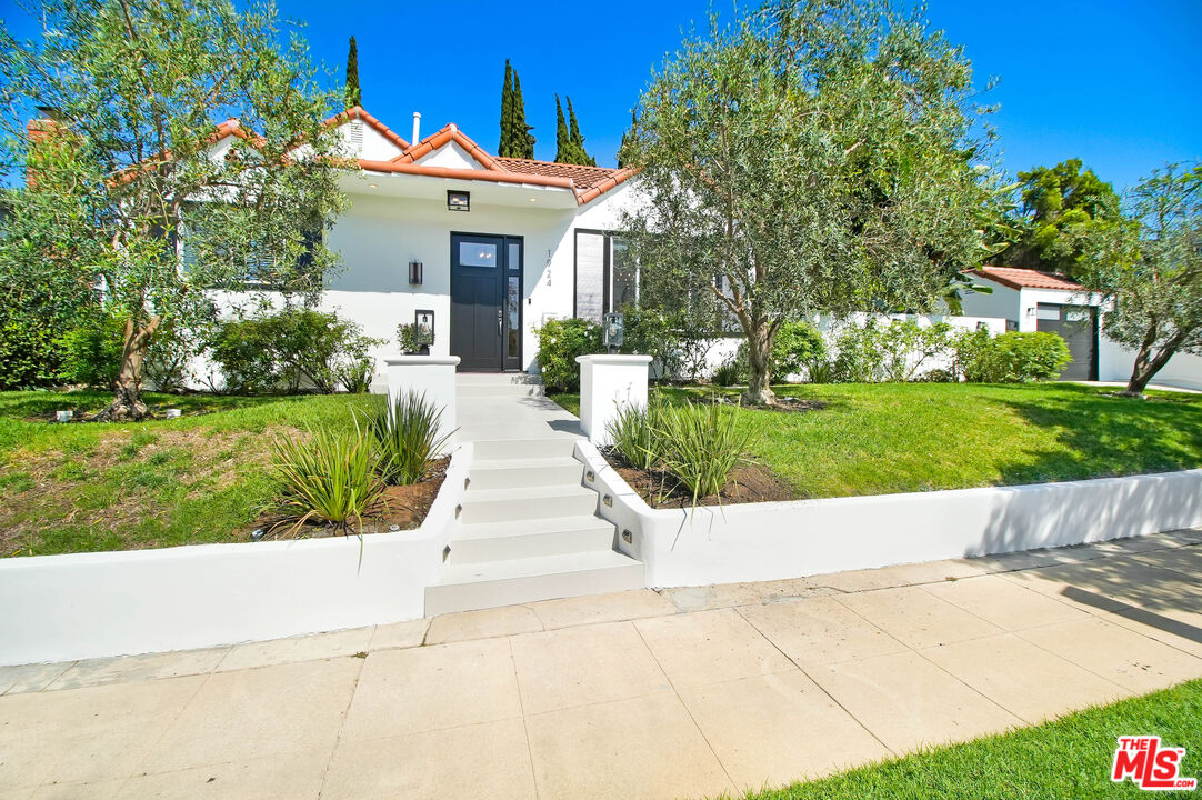 a view of a house with a yard and potted plants