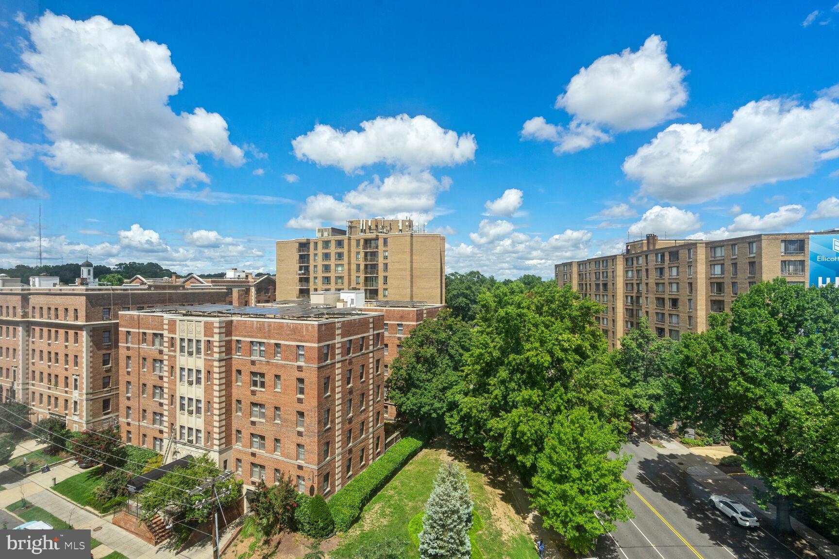 a view of a multi story residential apartment building with yard and retail shops