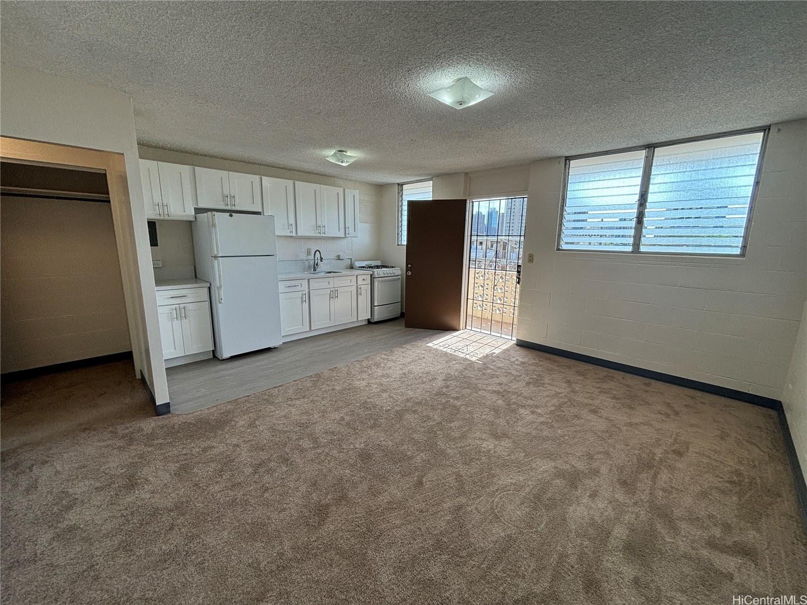 a view of a kitchen with refrigerator and white cabinets