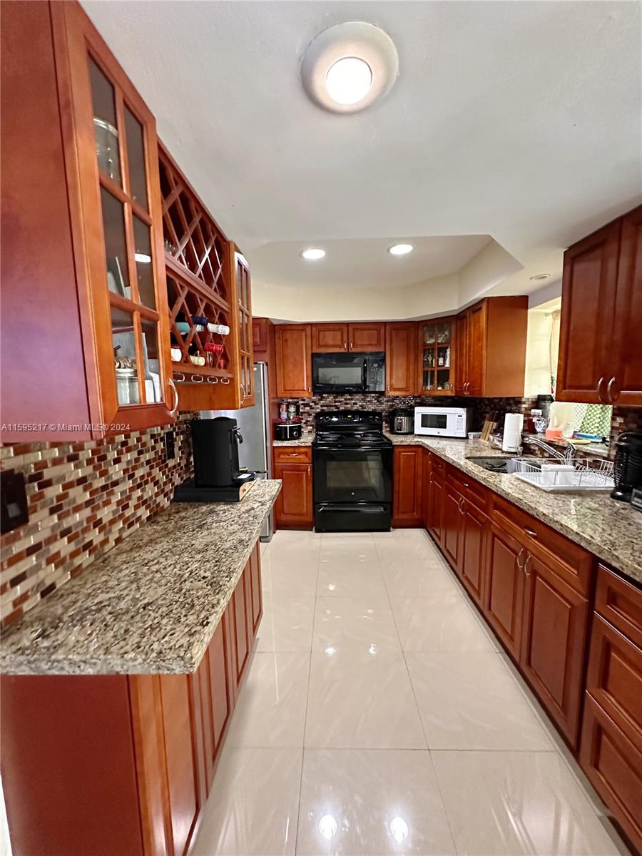 a large kitchen with stainless steel appliances granite countertop a stove a sink and a microwave