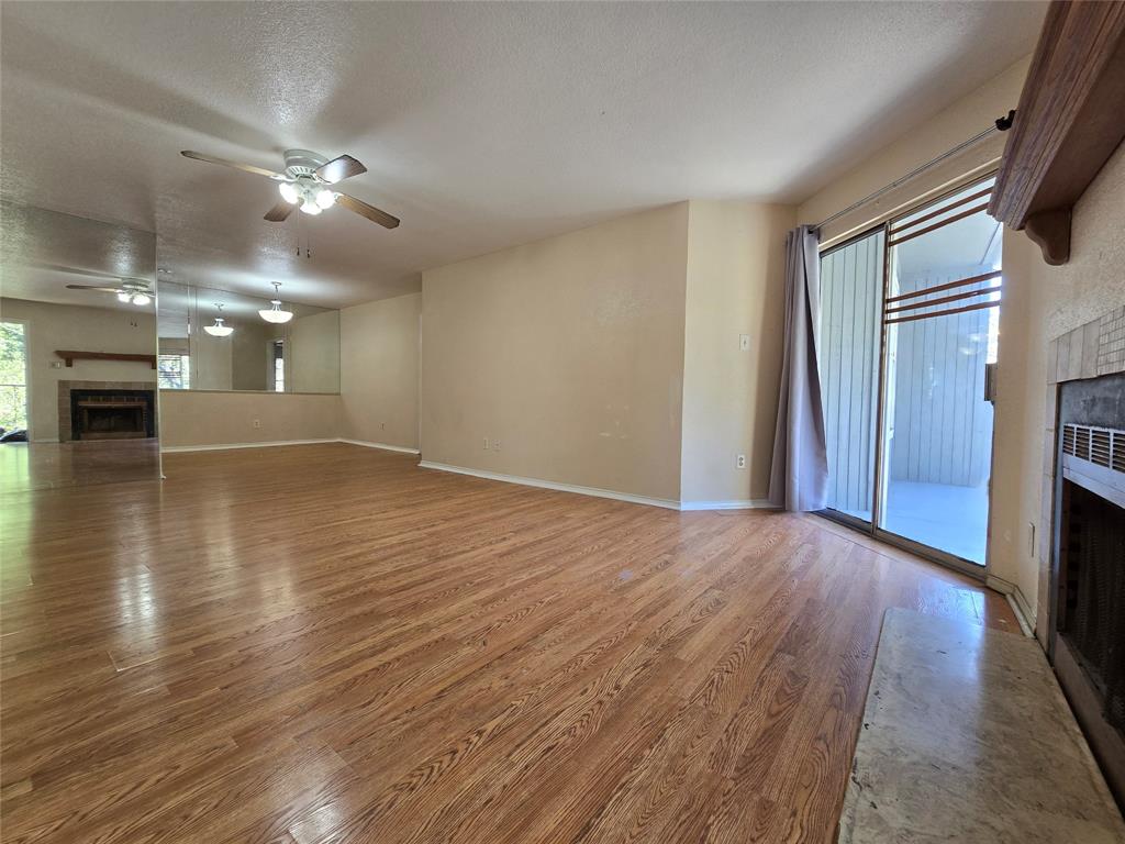 a view of an empty room with wooden floor and a kitchen