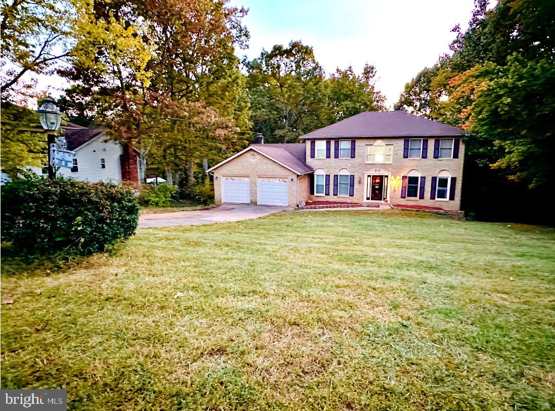 a view of a house next to a big yard and large trees