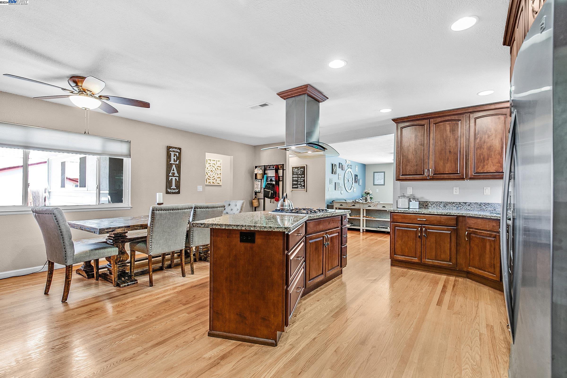 a kitchen with stainless steel appliances granite countertop wooden floors and wooden cabinets