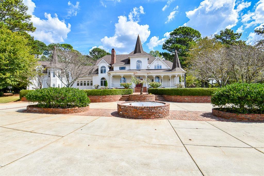 a front view of a building with garden and trees