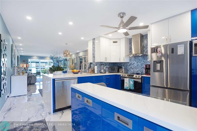 a kitchen with stainless steel appliances kitchen island granite countertop a refrigerator a oven a sink a dining table and chairs with wooden floor