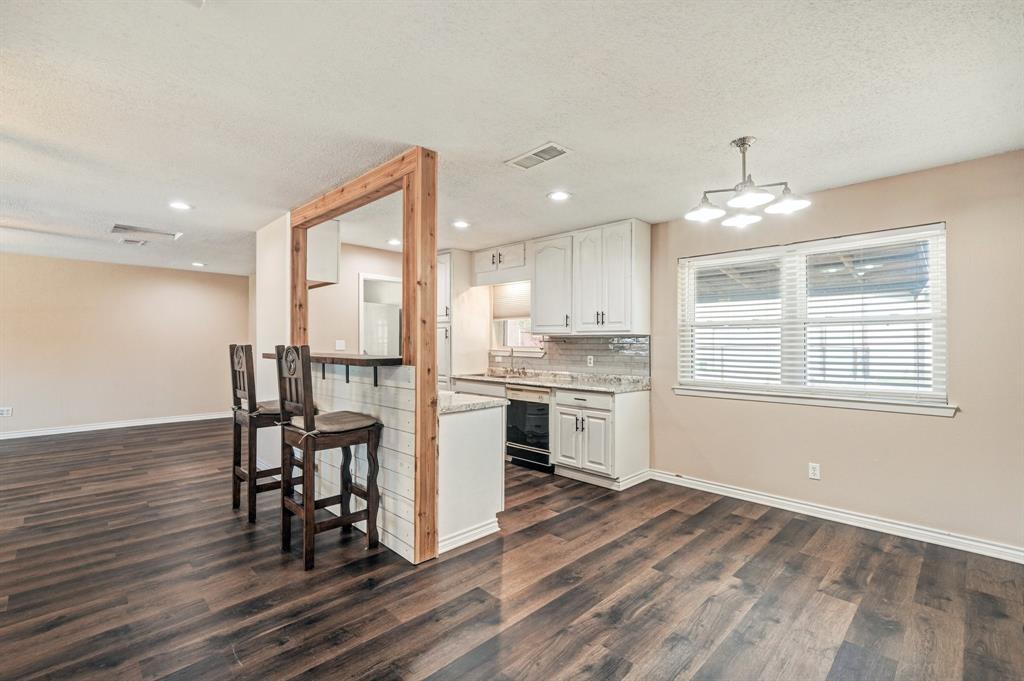 a kitchen with a table chairs a sink dishwasher window and cabinets