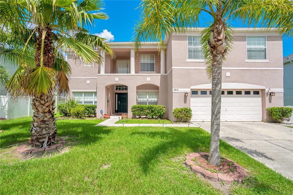 a front view of a house with a yard and palm trees