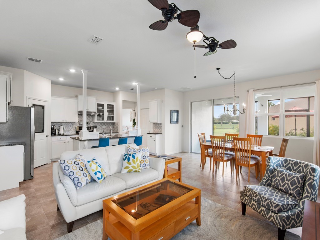 a living room with furniture kitchen view and a chandelier