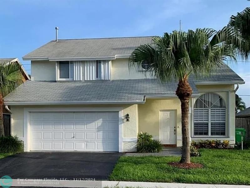 a front view of a house with a garden and palm trees