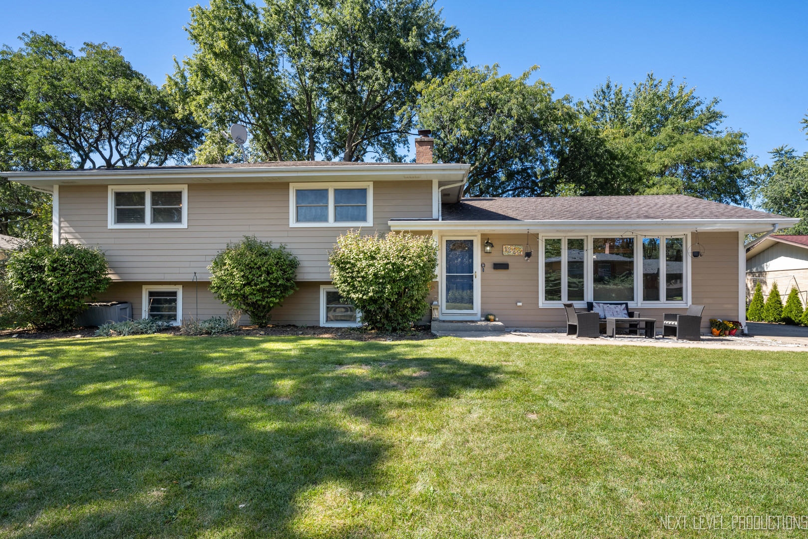 front view of a house with a patio yard and a large tree