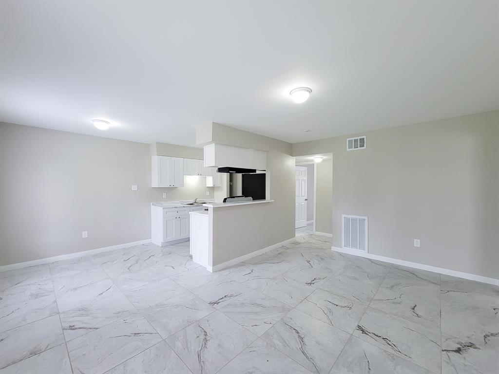 an empty room with kitchen view and a window