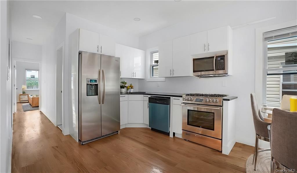 Kitchen featuring appliances with stainless steel finishes, white cabinets, and light hardwood / wood-style floors