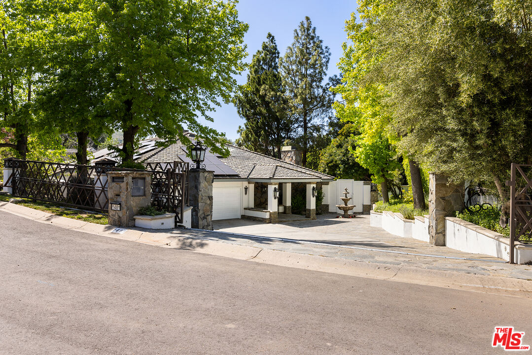 a tree is standing in front of house with yard and trees