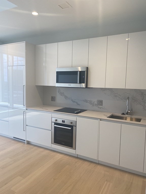 a kitchen with granite countertop white cabinets and stainless steel appliances