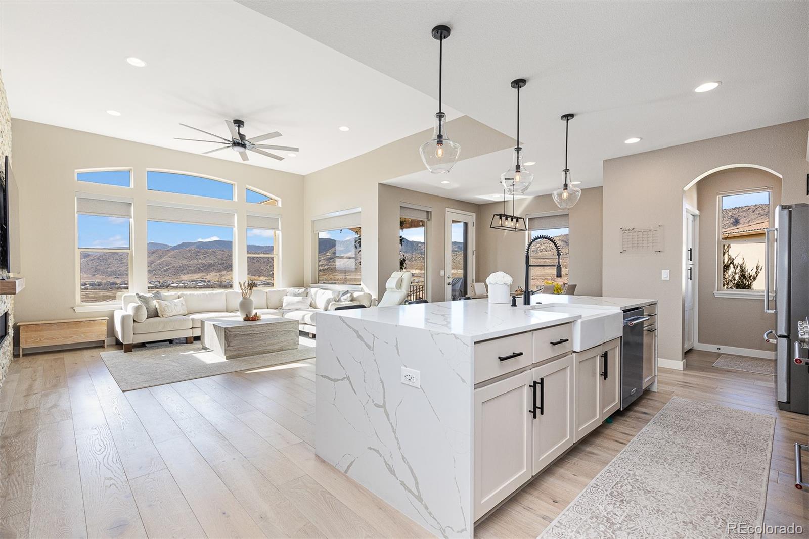 a large white kitchen with a large window a sink dishwasher and a stove with wooden floor