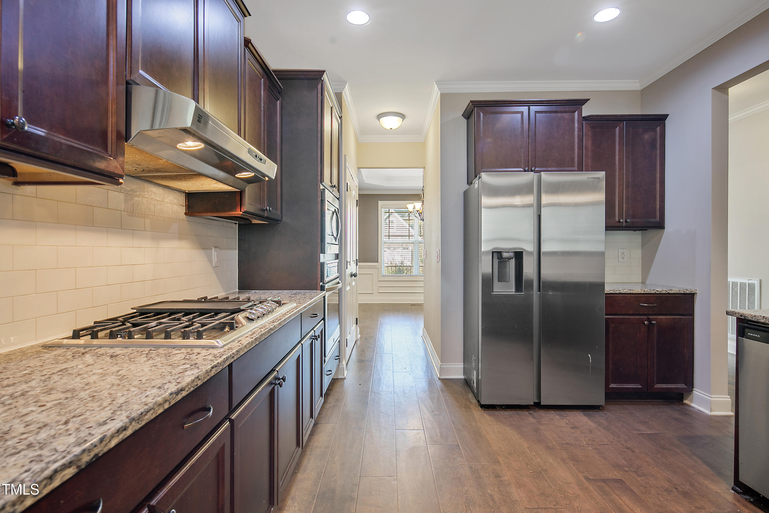 a kitchen with stainless steel appliances granite countertop a refrigerator a stove and a wooden floors