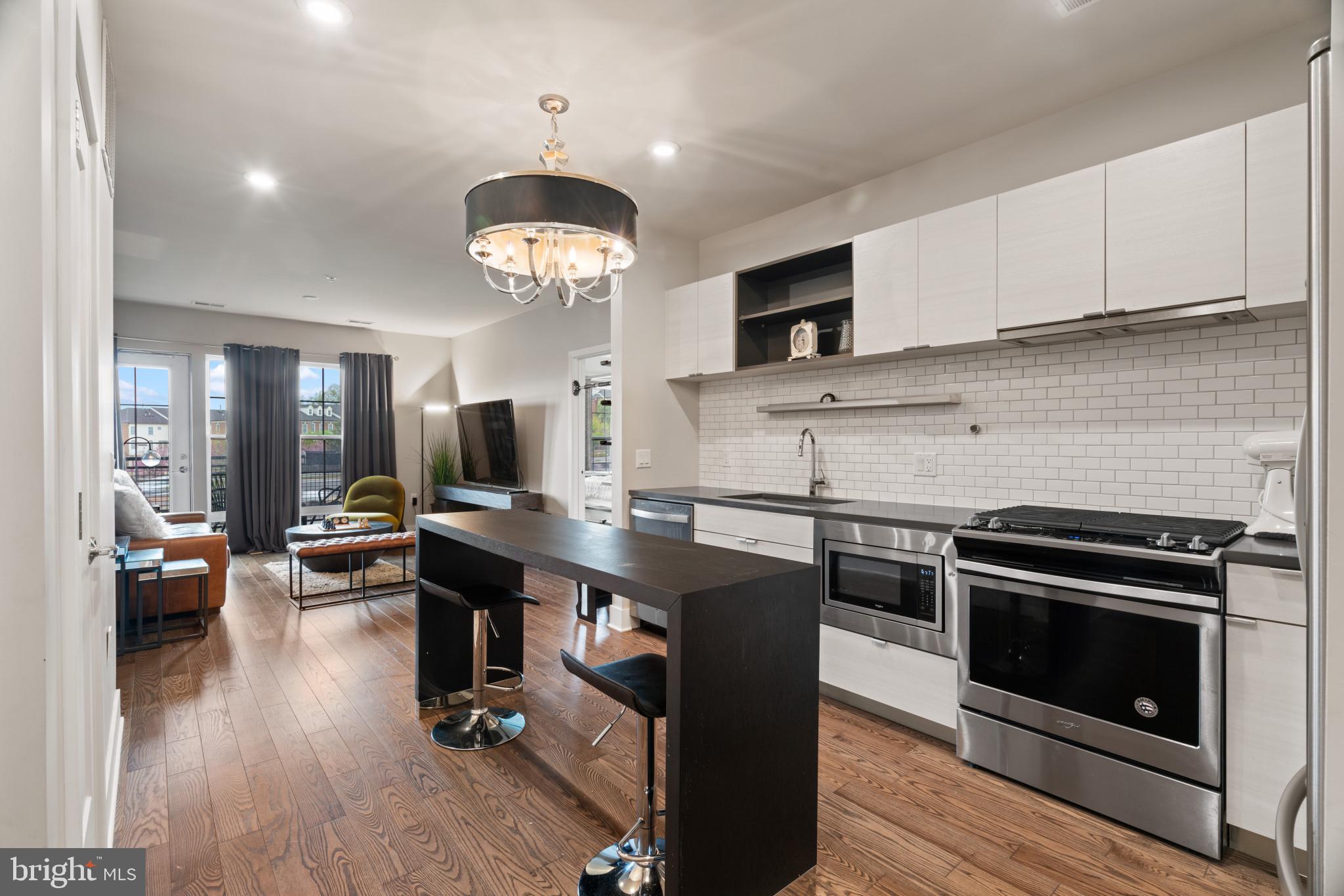 a kitchen with stainless steel appliances a stove center island wooden floor and cabinets