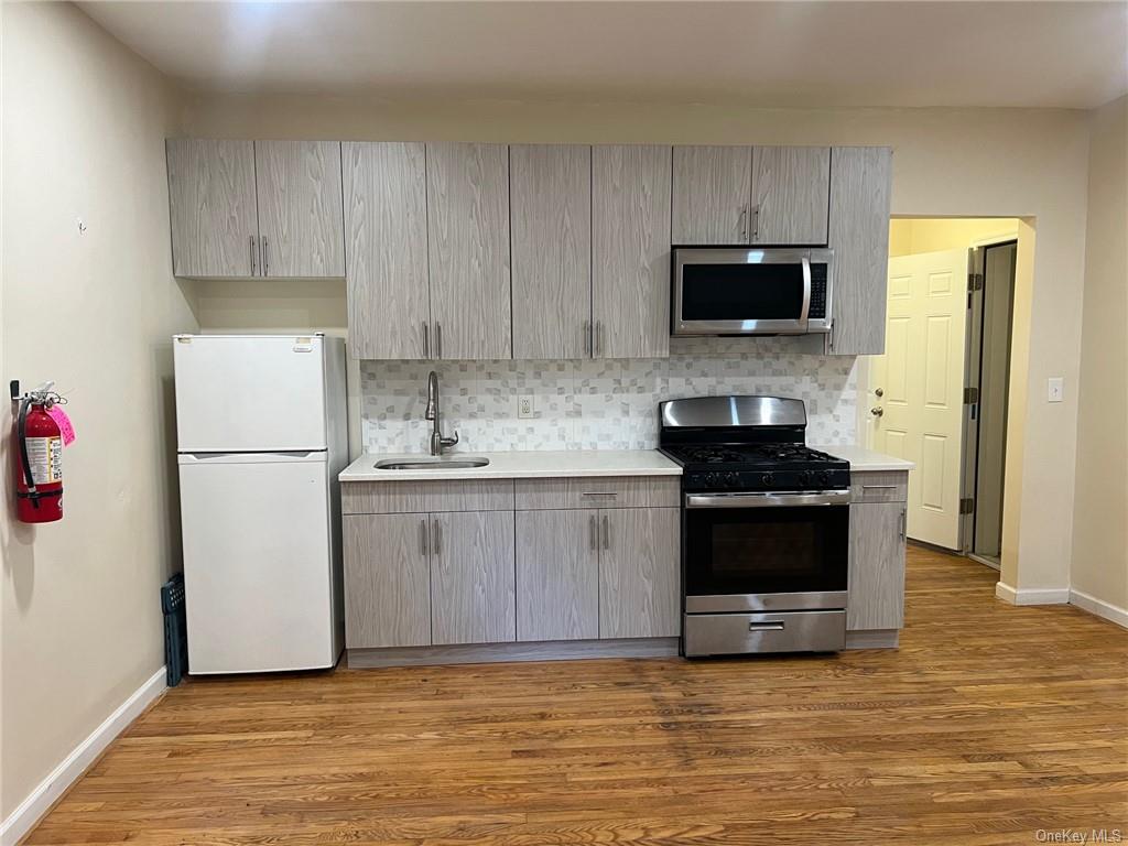 Kitchen with light hardwood / wood-style flooring, appliances with stainless steel finishes, sink, and gray cabinets