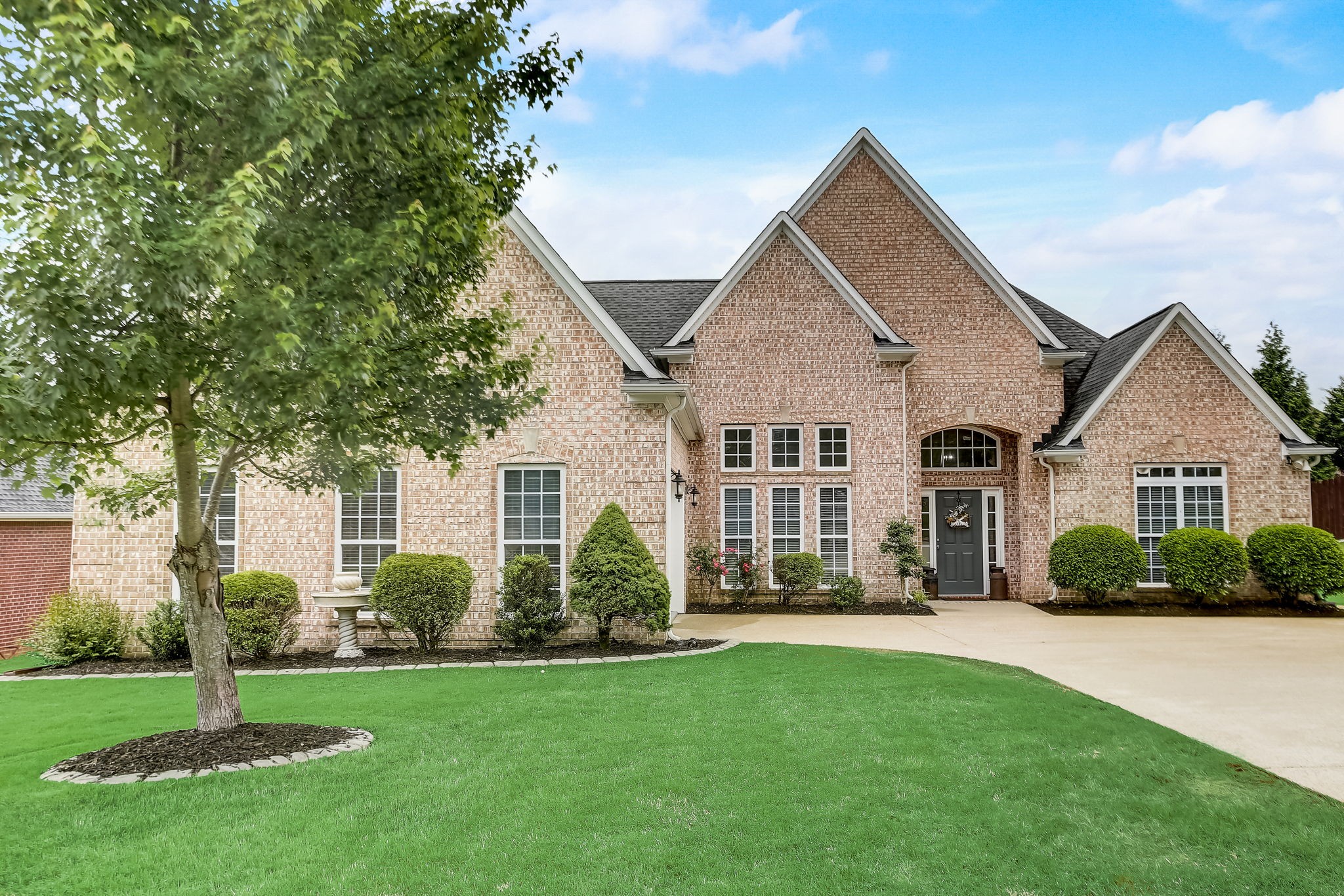 a front view of a house with a yard and green space