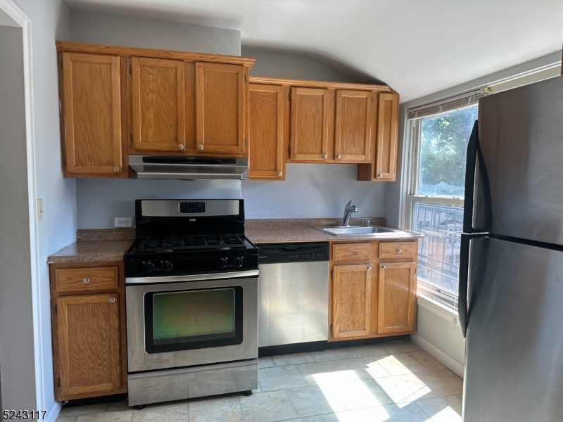 a kitchen with granite countertop a refrigerator stove top oven and sink