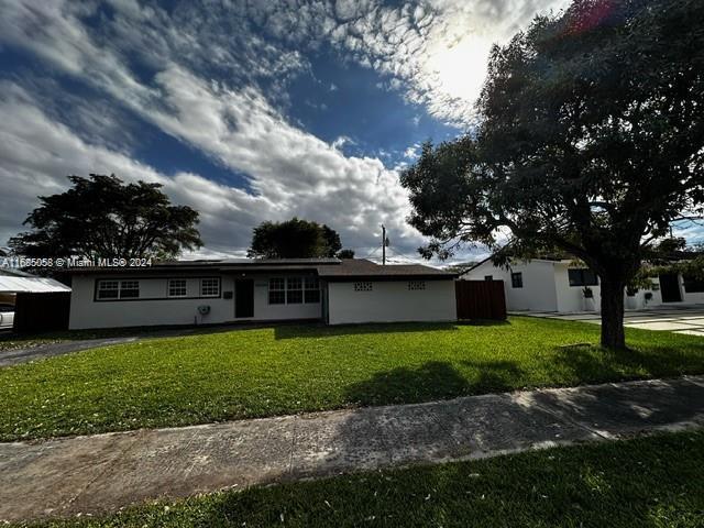 a view of a house with a yard and a large tree