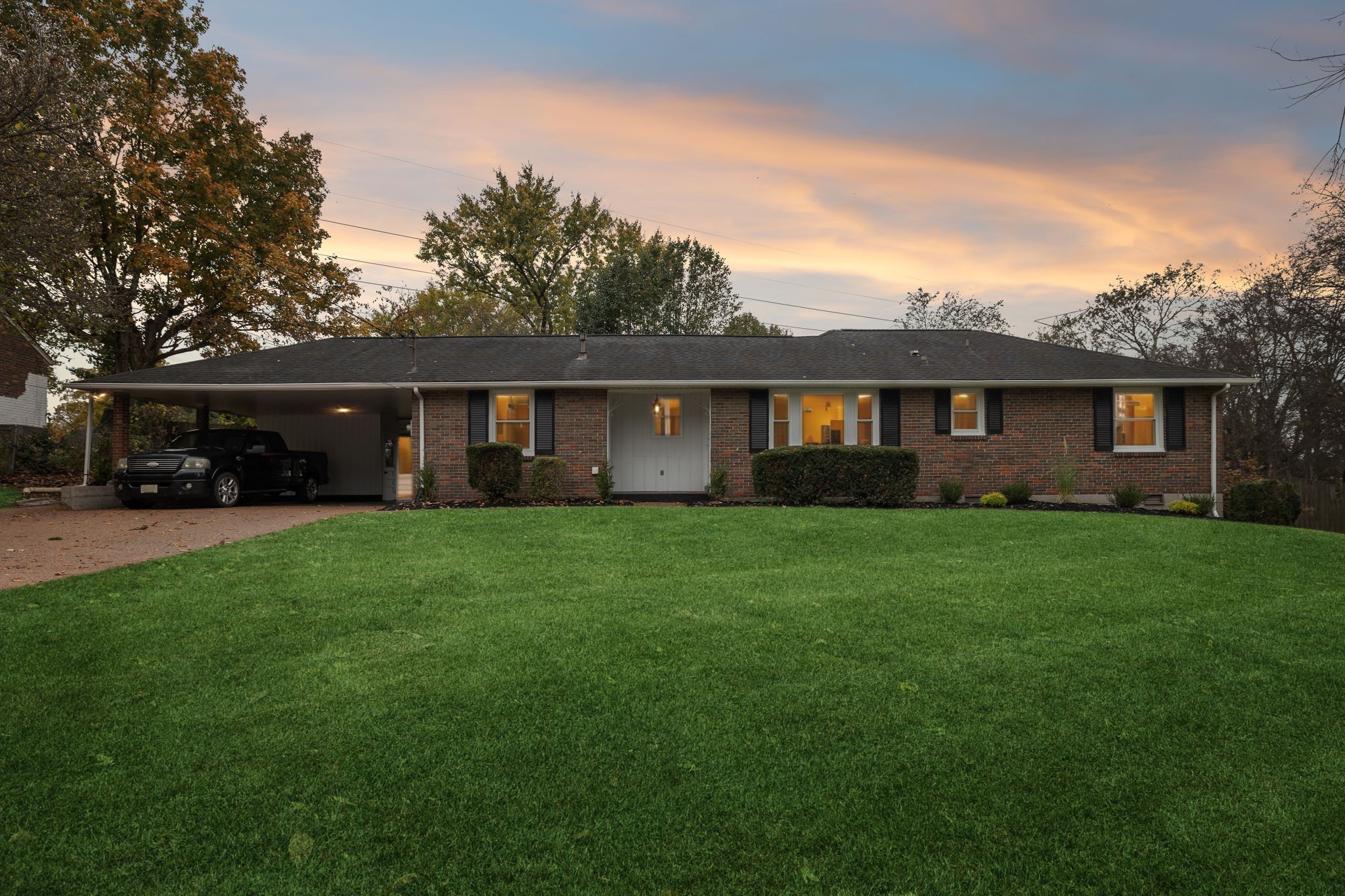 a view of house in front of a big yard with large trees