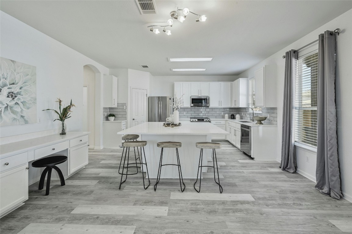 a kitchen with stainless steel appliances kitchen island granite countertop a table chairs sink and cabinets