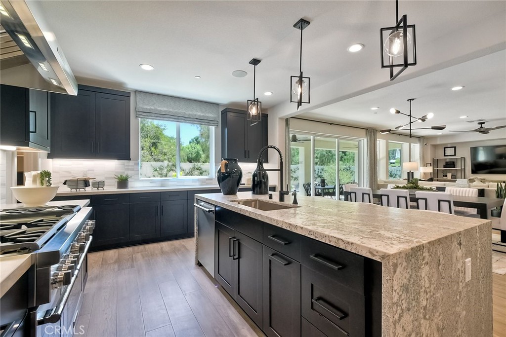 a kitchen with a stove center island with wooden floor cabinets and a window