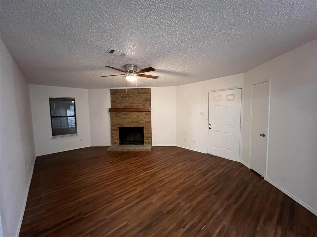 a view of empty room with wooden floor and fireplace