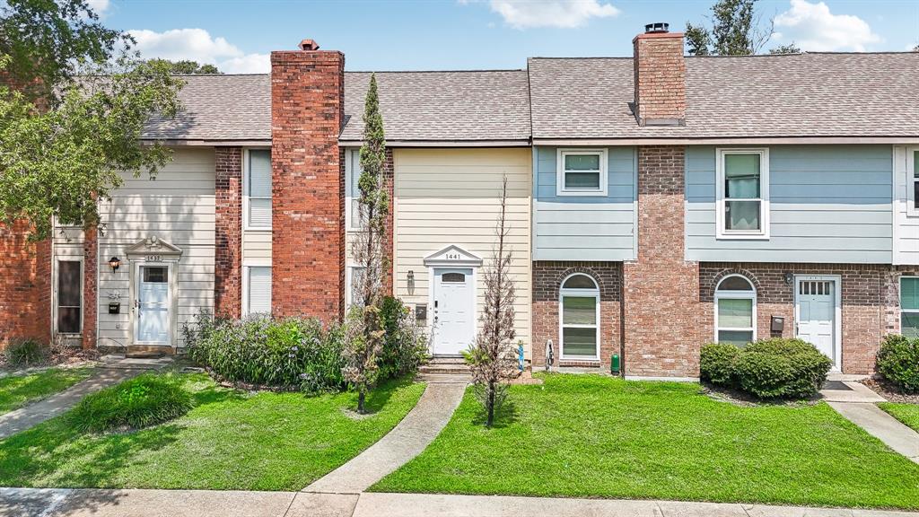 a view of a house with brick walls and a yard with plants