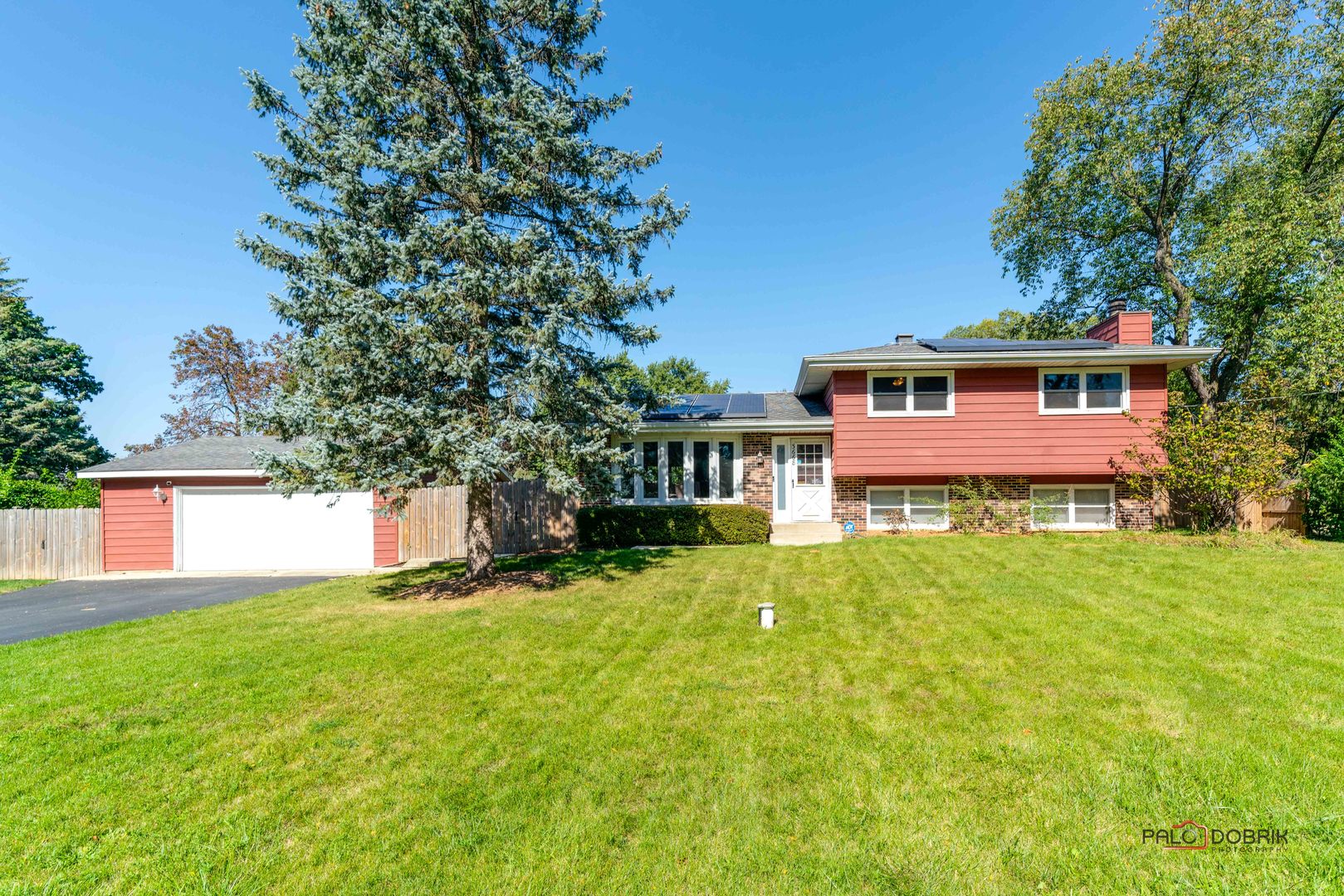 a front view of house with yard and trees in the background