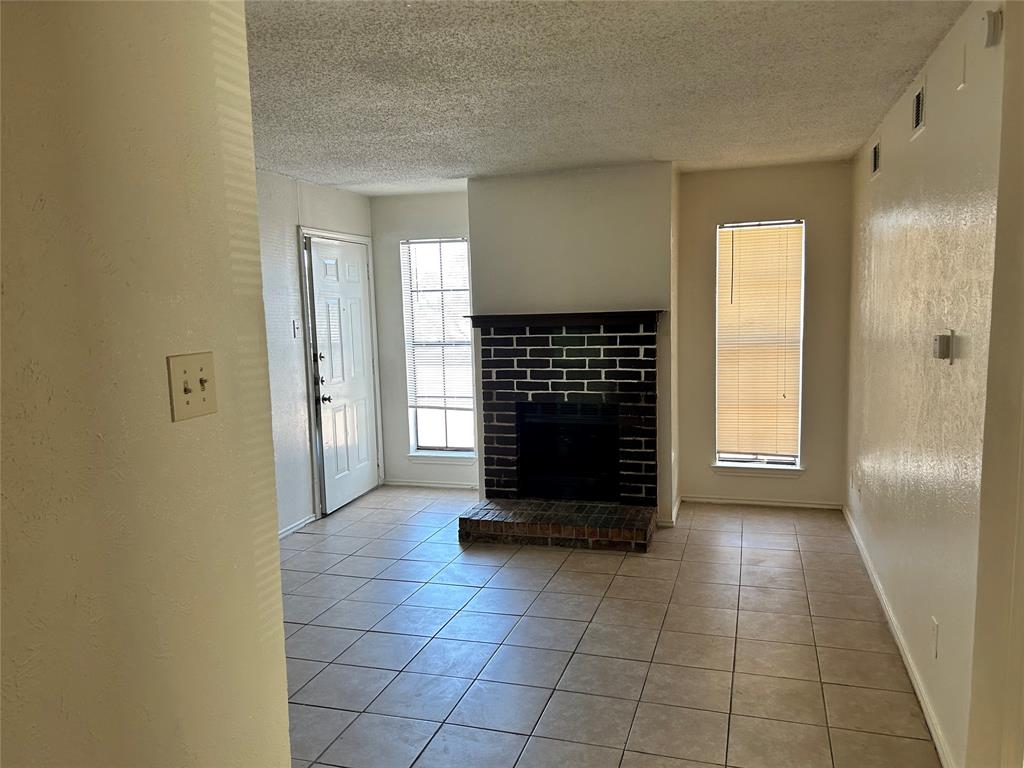 a view of an empty room with a fireplace and a window