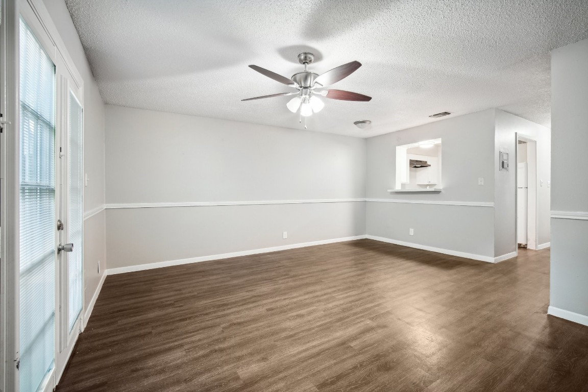 an empty room with wooden floor fan and windows