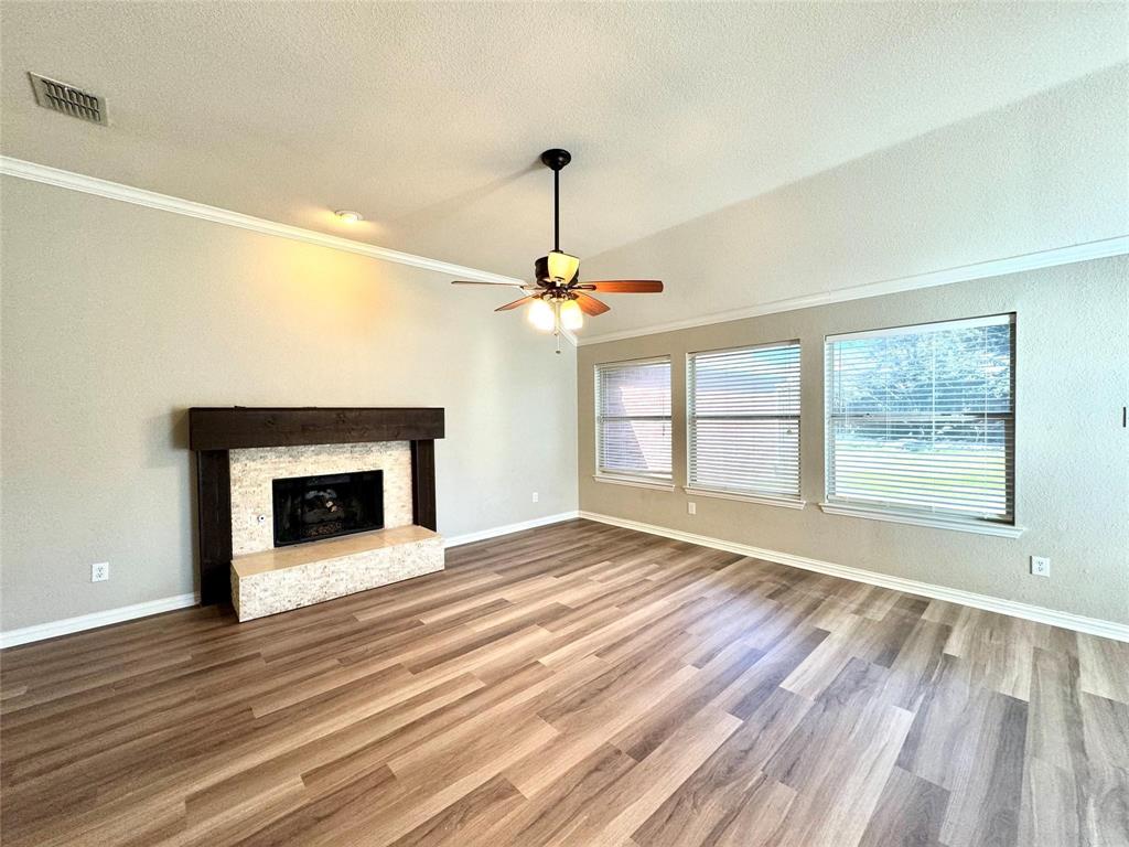 a view of an empty room with wooden floor fireplace and a window