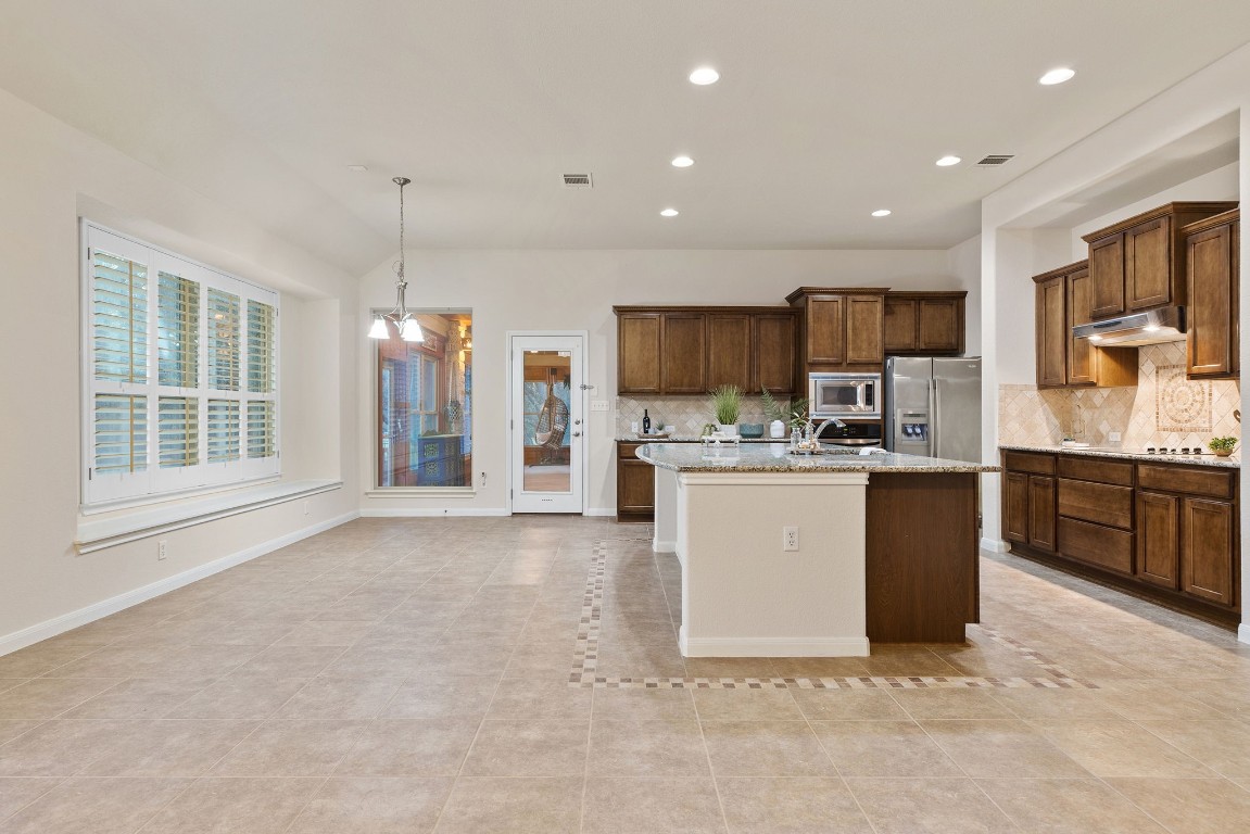 a large kitchen with kitchen island a large counter top stainless steel appliances and cabinets