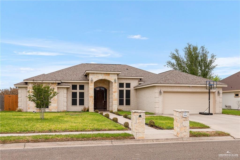 View of front of property featuring a front lawn and a garage