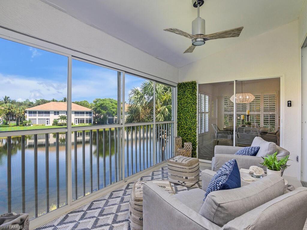 Sunroom featuring ceiling fan with notable chandelier, a water view, and vaulted ceiling