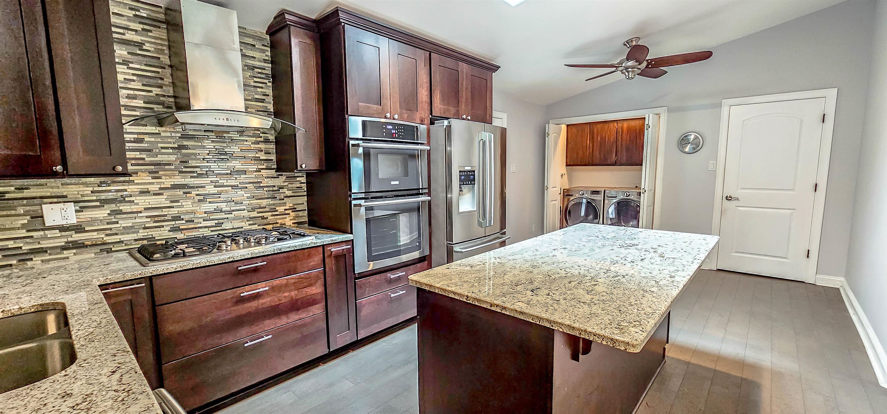 a kitchen with stainless steel appliances kitchen island granite countertop a stove refrigerator and microwave