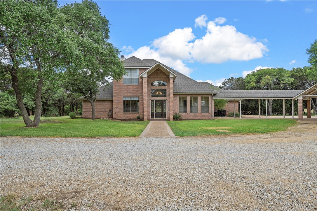 a view of house in front of a big yard with large trees