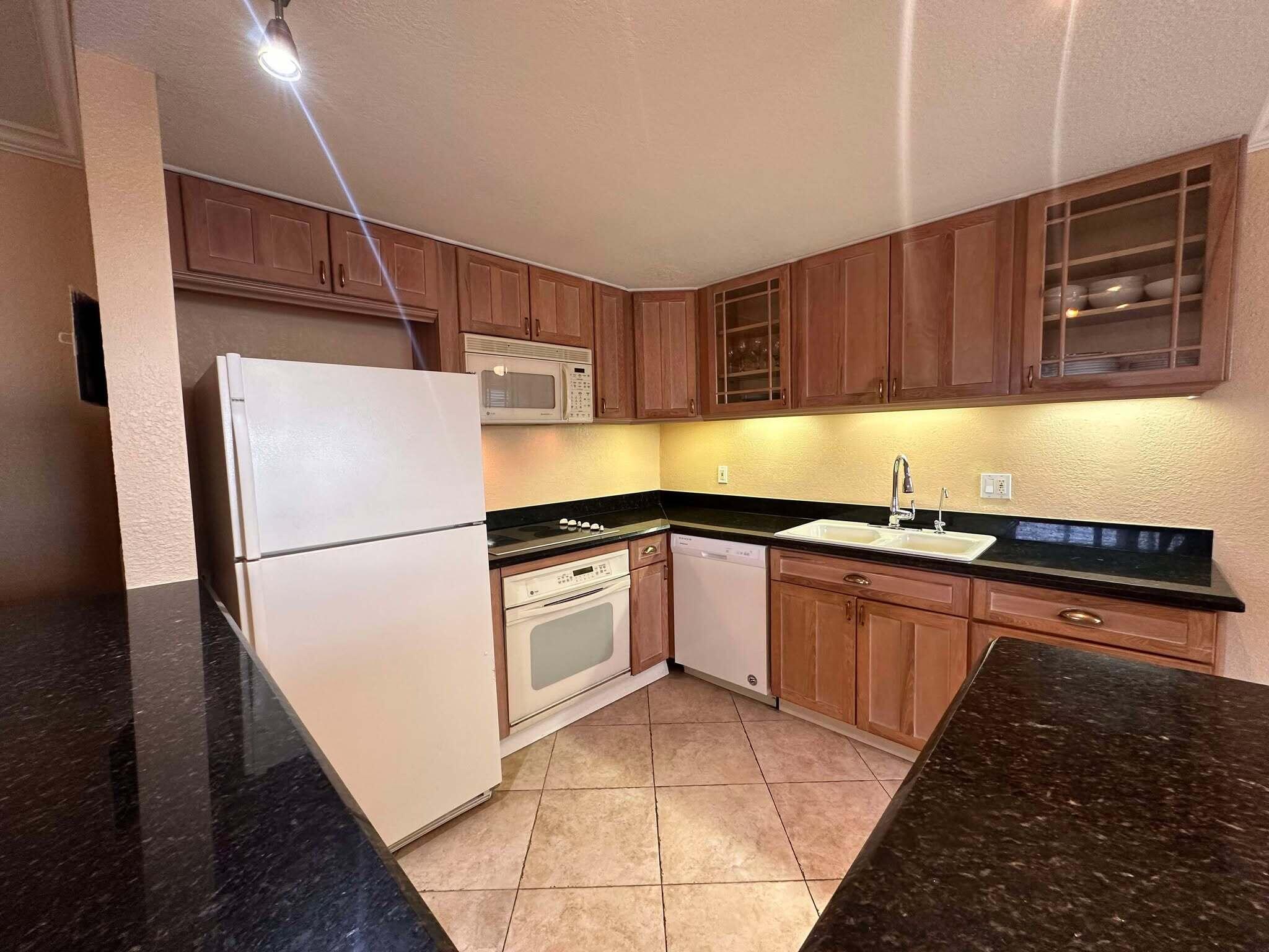 a kitchen with granite countertop a refrigerator and a sink