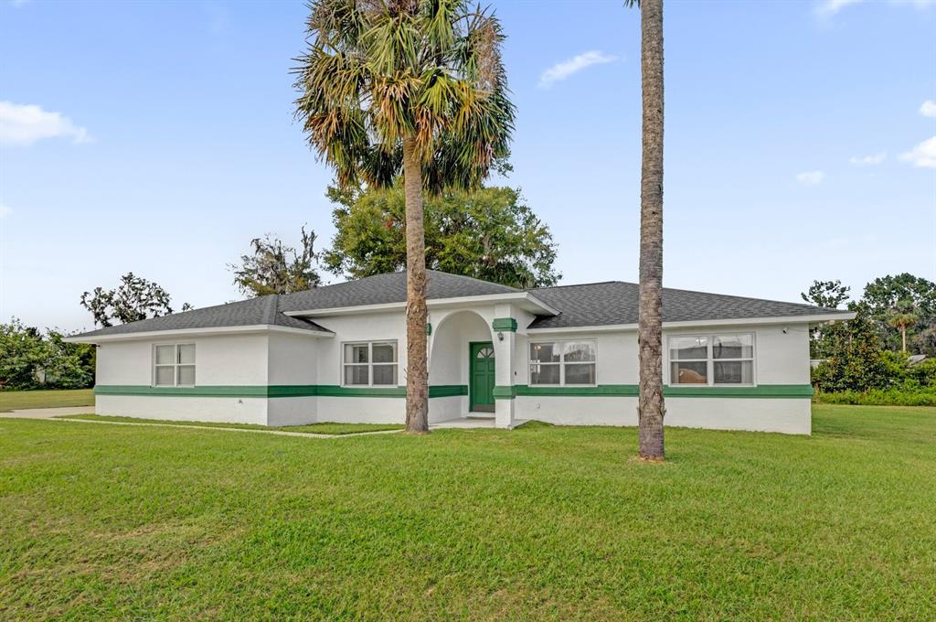 a view of a house with a big yard and palm trees