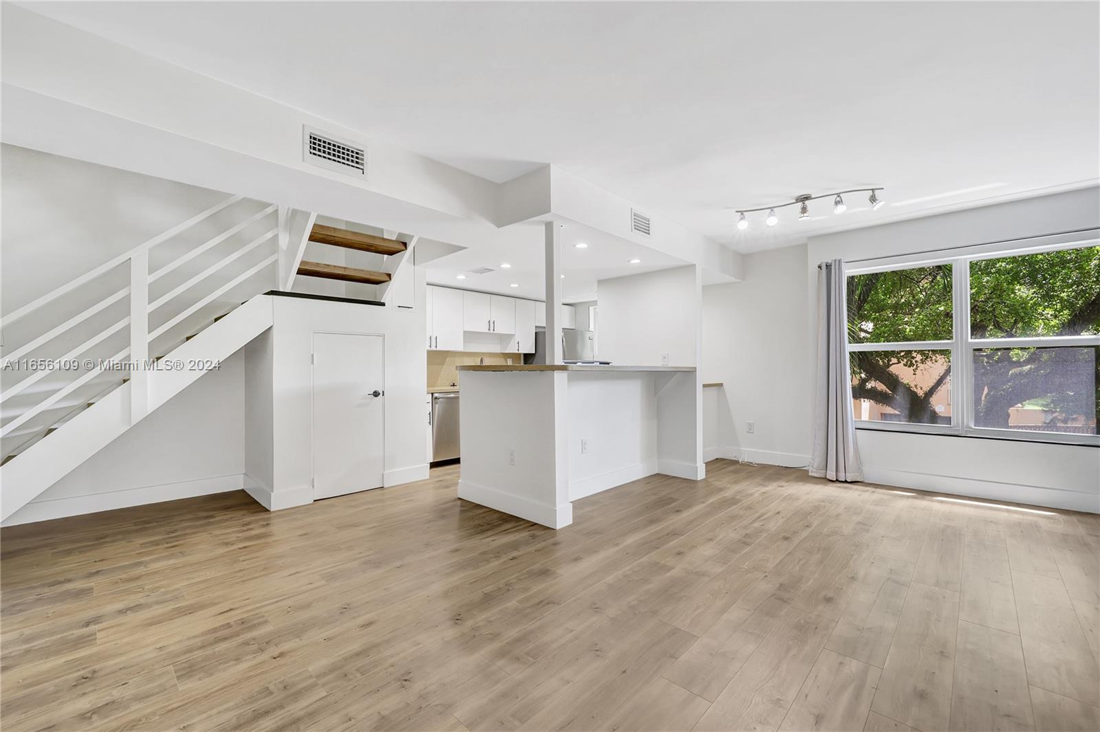 a view of a kitchen with wooden floor and a window