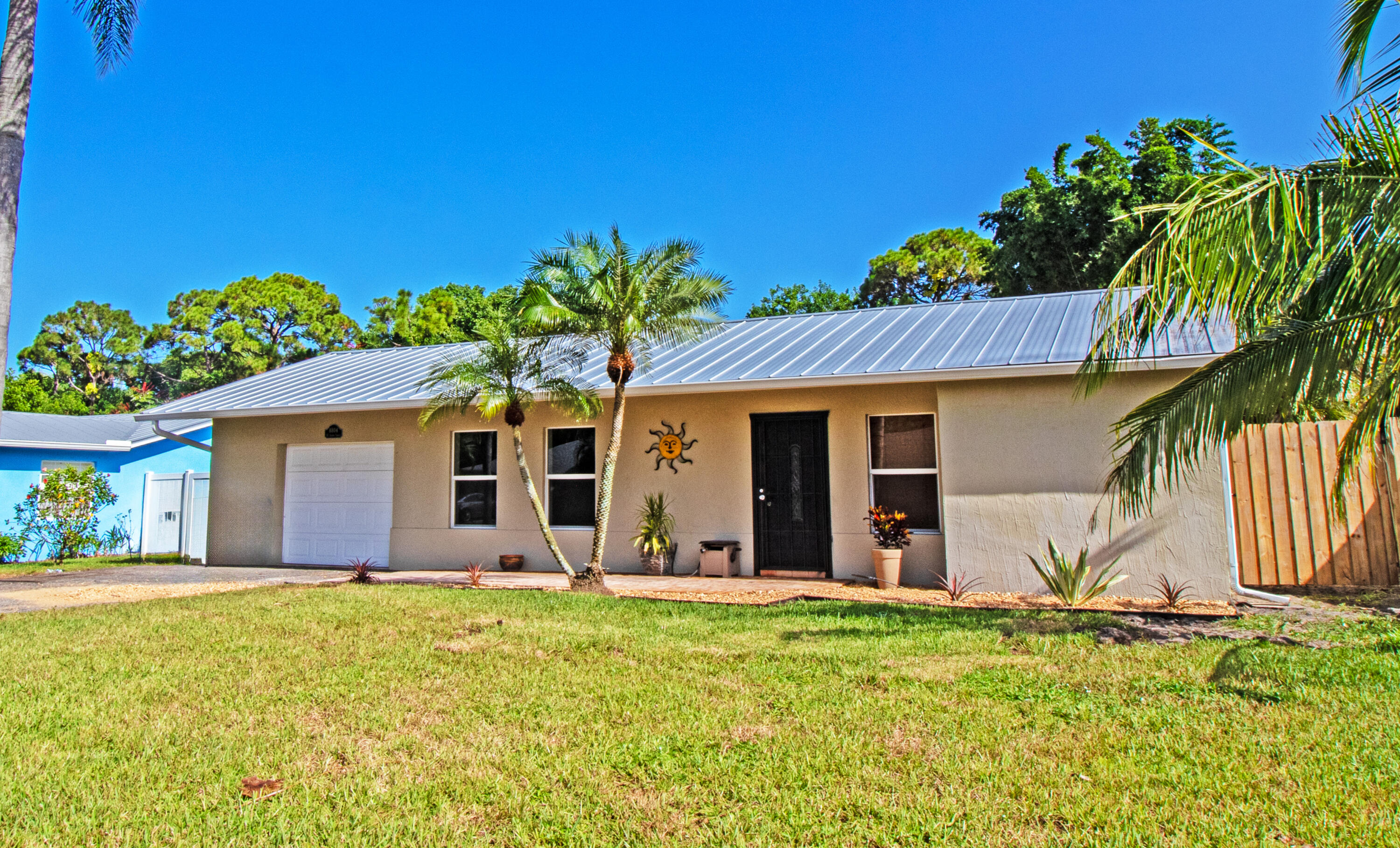 a view of a house with small yard plants and a large tree