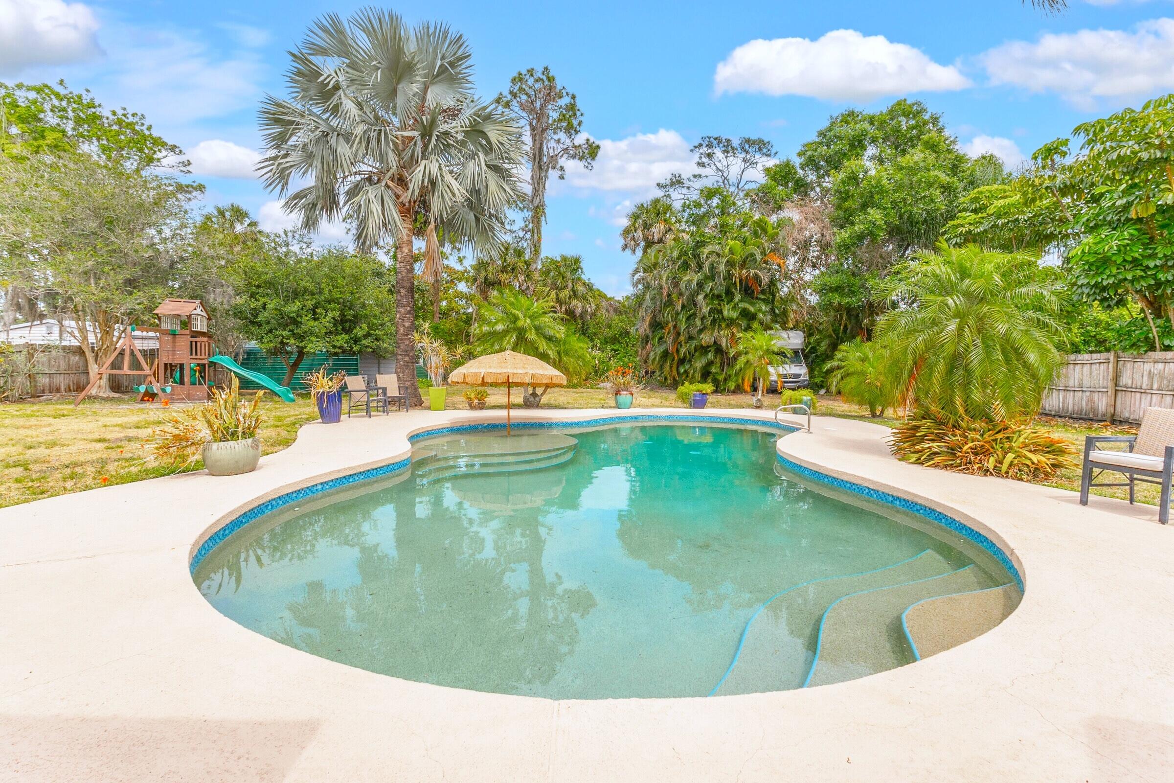 a view of a swimming pool with an outdoor seating area and trees around