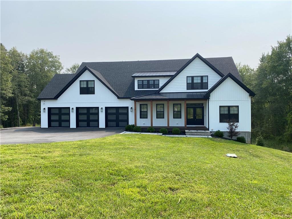 Modern inspired farmhouse featuring a front lawn, a garage, and covered porch