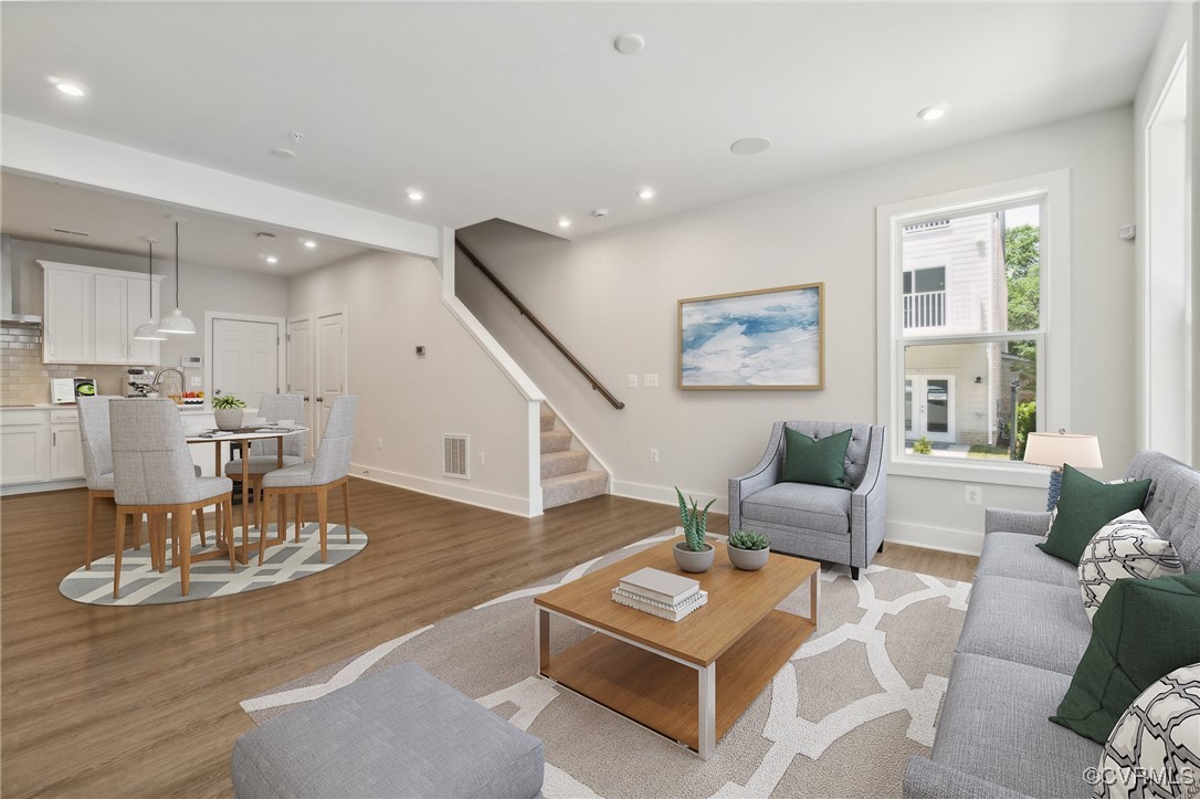 a living room with furniture and a dining table with wooden floor