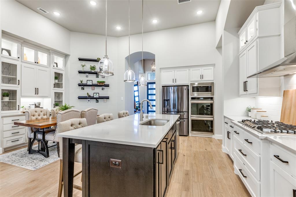 a kitchen with stainless steel appliances kitchen island granite countertop a table chairs and a refrigerator