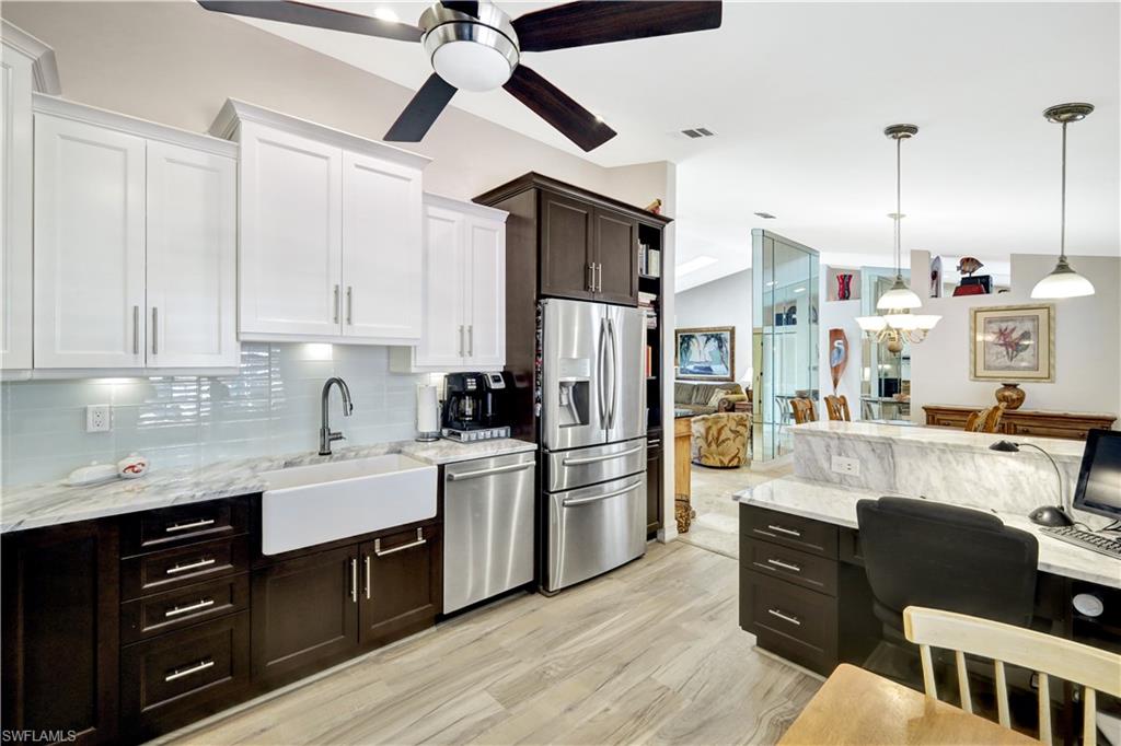 a kitchen with stainless steel appliances kitchen island granite countertop a refrigerator a sink dishwasher a dining table and chairs with wooden floor