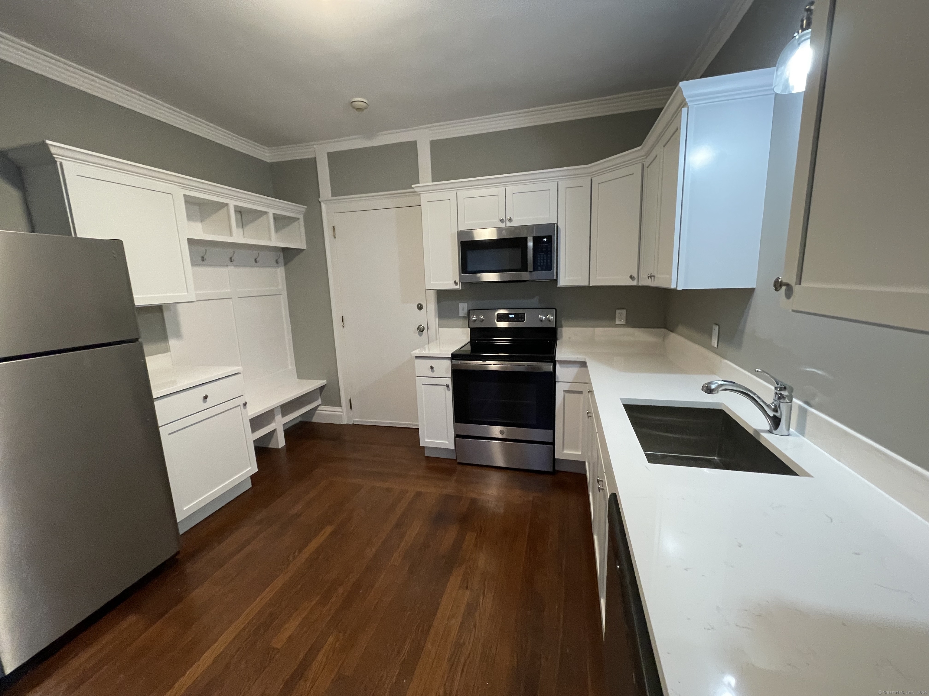 a kitchen with granite countertop a refrigerator a sink a stove and white cabinets